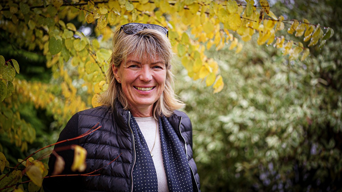 Helle Borup Friberg står ved et træ og smiler til kameraet