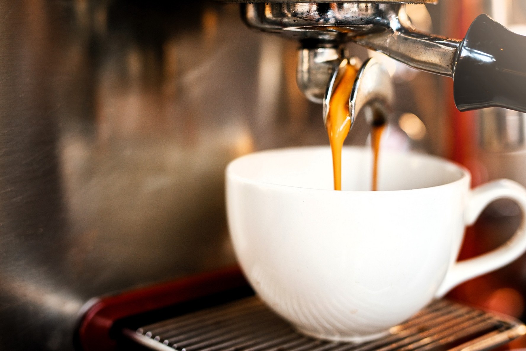 En kaffemaskine fylder kaffe på en kop