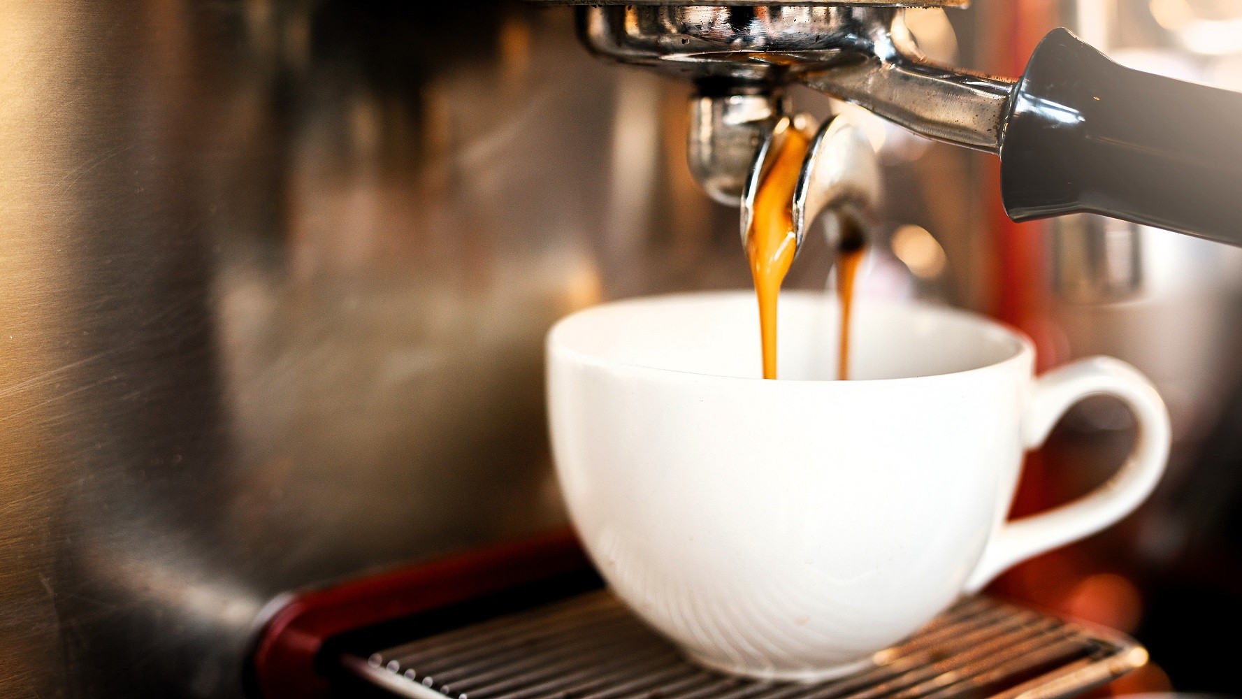 En kaffemaskine fylder kaffe på en kop