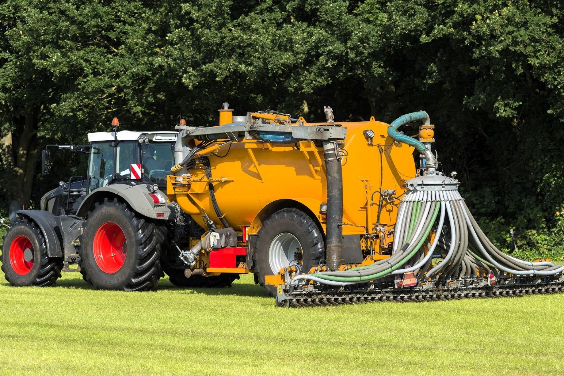 En traktor kører på en mark og spreder gylle
