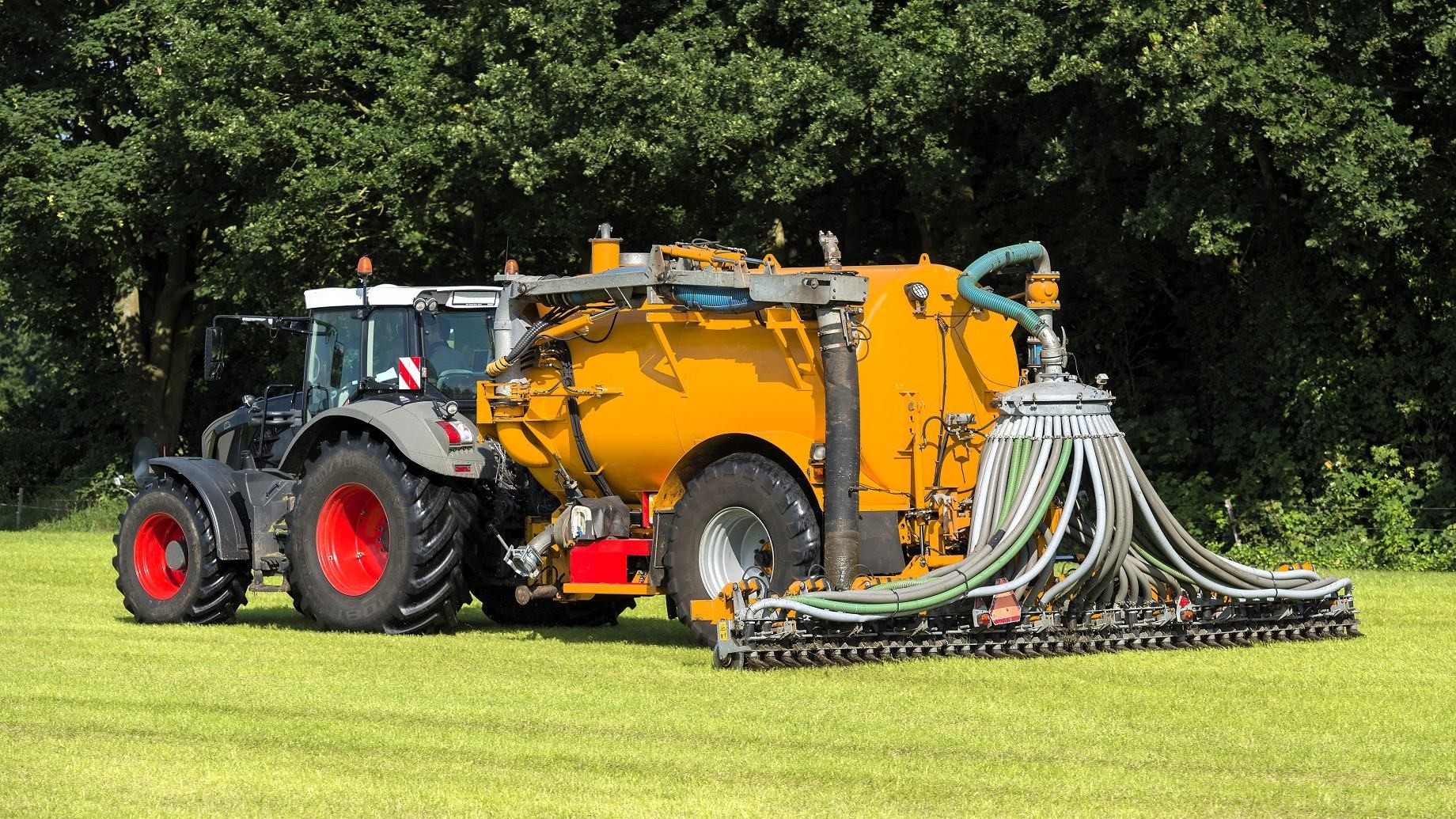 En traktor kører på en mark og spreder gylle