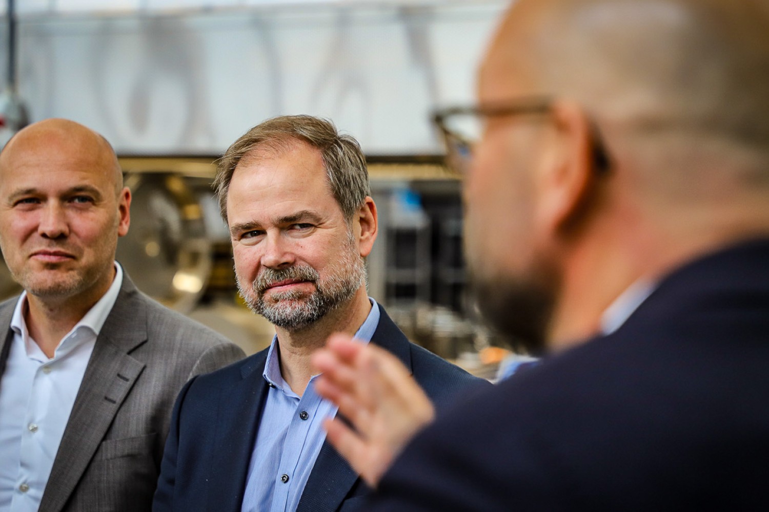 Nicolai Wammen og Anders Kühnau (t.v.) står og ser på Rasmus Prehn, der taler
