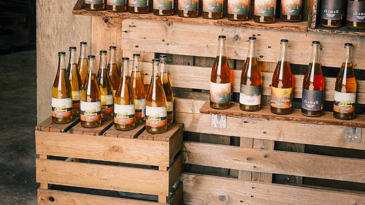 Ciderflasker står på trækasser og hylder