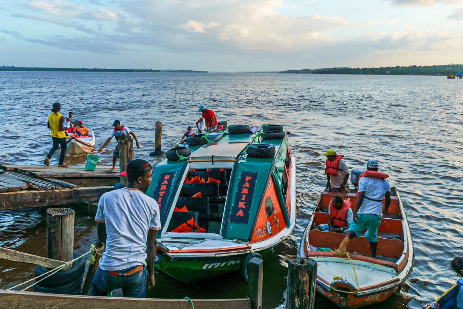 Folk står ved fortøjede både på kysten