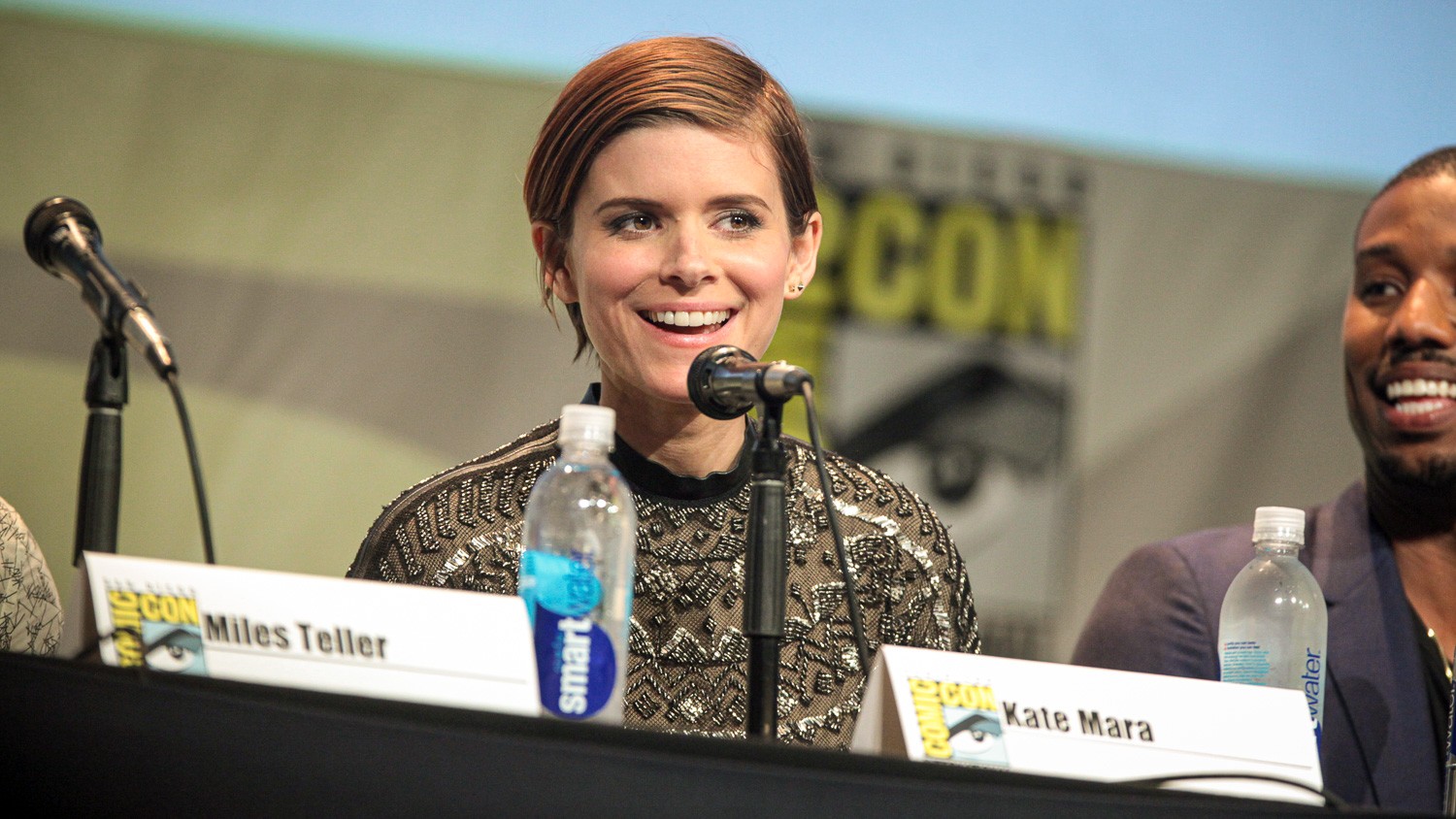 Kate Mara sidder ved en mikrofon og smiler til ComicCon