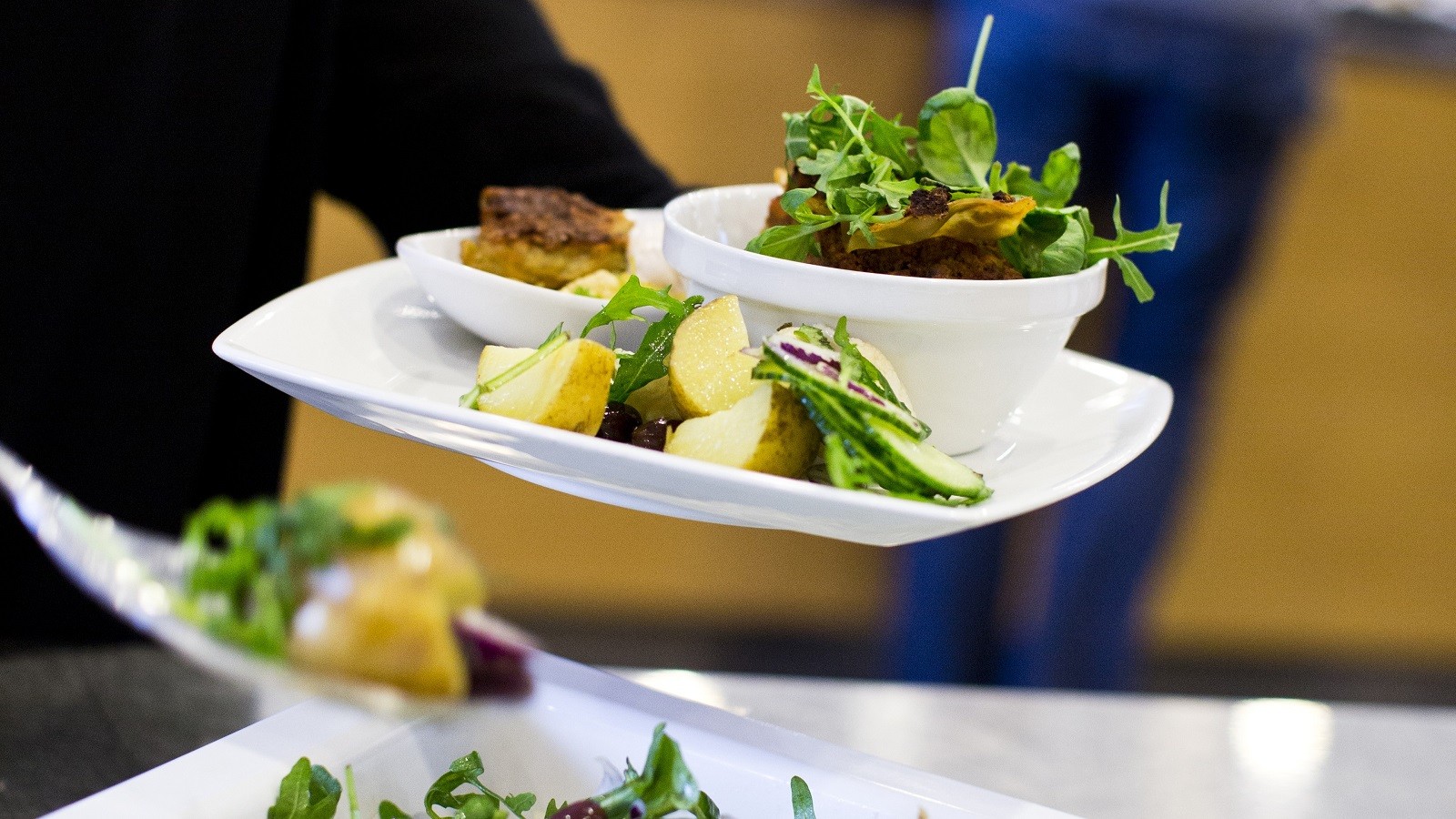 Kantinegæst i buffet fylder tallerken med grøntsager