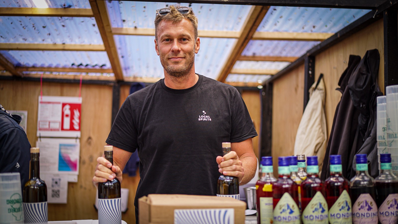 Jeppe står i baren med hver hånd om en flaske